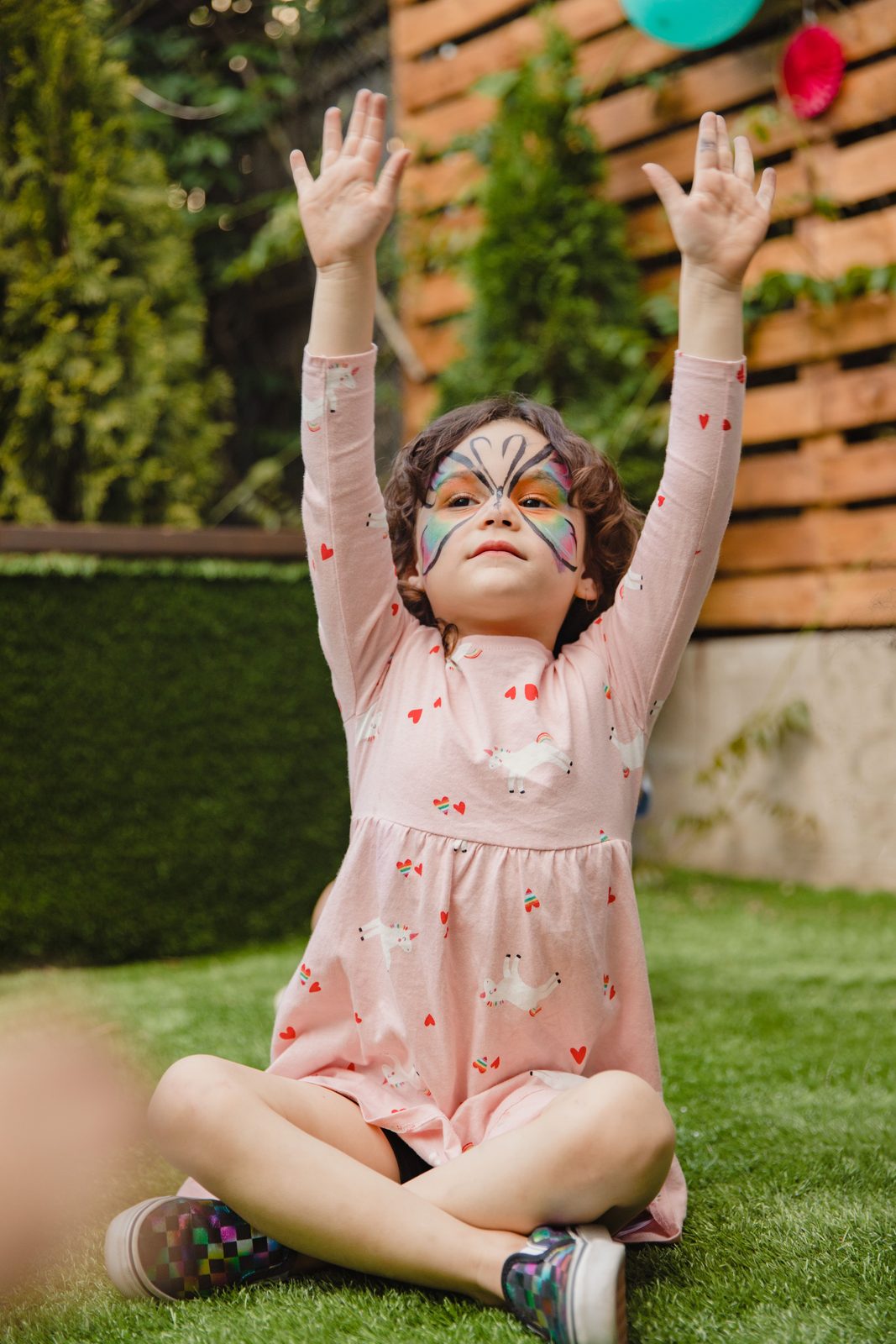 Girl with butterfly face paint raising her hands with joy