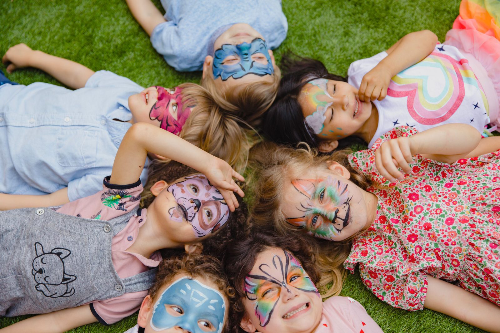 Group of children with colourful face paint at an outdoor party